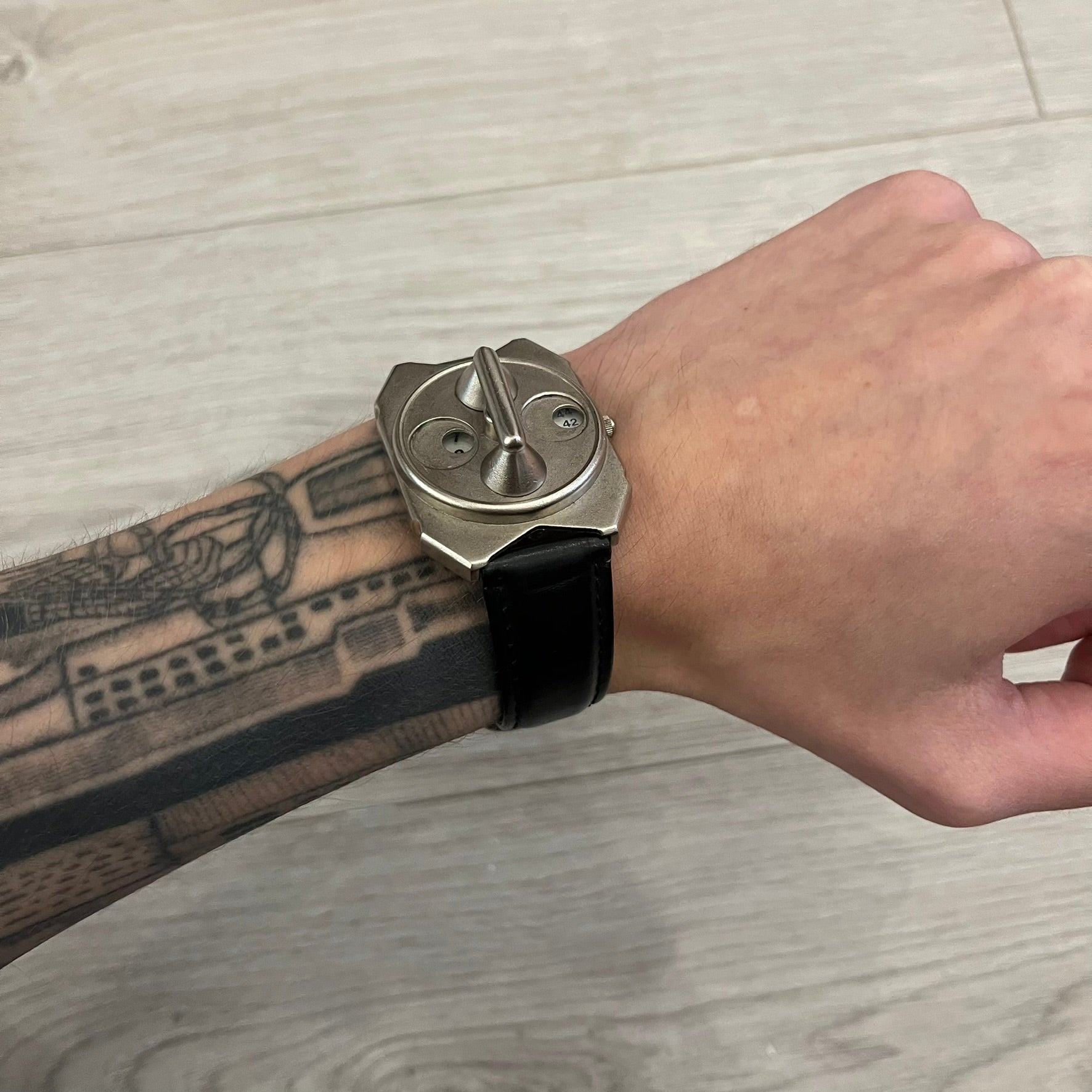 Hi-Tek Alexander “Jump Hour” 90's Analog Watch with a rare octagonal steel case and innovative rotation disc display. Hours appear in the left window and minutes in the right, revealed by the unique turnable cover. Made in England, this vintage 1990s watch features a chrome-plated stainless steel case, genuine leather strap, and an original design by Alexander Tasou of Hi-Tek Designs London. A true collector’s piece that is no longer in production.