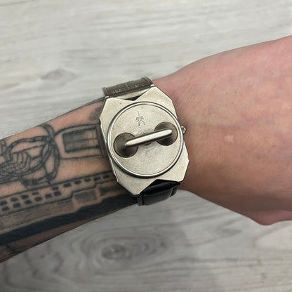 Hi-Tek Alexander “Jump Hour” 90's Analog Watch with a rare octagonal steel case and innovative rotation disc display. Hours appear in the left window and minutes in the right, revealed by the unique turnable cover. Made in England, this vintage 1990s watch features a chrome-plated stainless steel case, genuine leather strap, and an original design by Alexander Tasou of Hi-Tek Designs London. A true collector’s piece that is no longer in production.