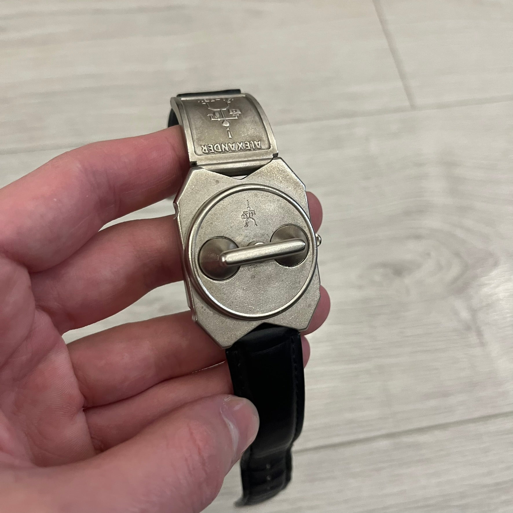 Hi-Tek Alexander “Jump Hour” 90's Analog Watch with a rare octagonal steel case and innovative rotation disc display. Hours appear in the left window and minutes in the right, revealed by the unique turnable cover. Made in England, this vintage 1990s watch features a chrome-plated stainless steel case, genuine leather strap, and an original design by Alexander Tasou of Hi-Tek Designs London. A true collector’s piece that is no longer in production.