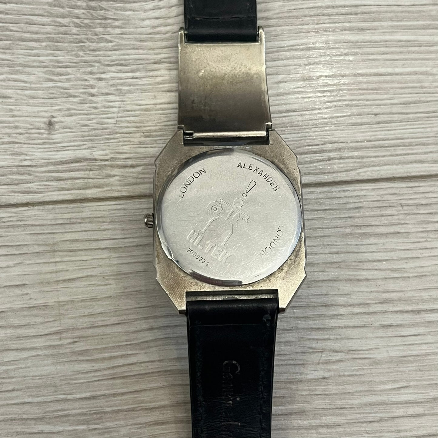 Hi-Tek Alexander “Jump Hour” 90's Analog Watch with a rare octagonal steel case and innovative rotation disc display. Hours appear in the left window and minutes in the right, revealed by the unique turnable cover. Made in England, this vintage 1990s watch features a chrome-plated stainless steel case, genuine leather strap, and an original design by Alexander Tasou of Hi-Tek Designs London. A true collector’s piece that is no longer in production.