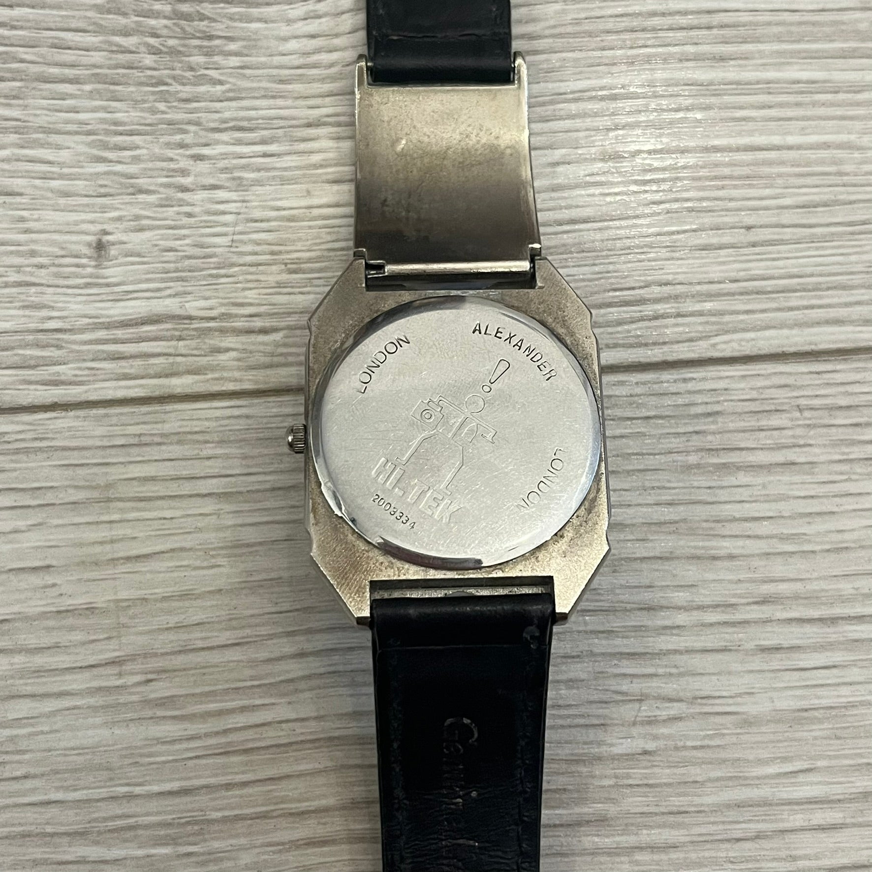 Hi-Tek Alexander “Jump Hour” 90's Analog Watch with a rare octagonal steel case and innovative rotation disc display. Hours appear in the left window and minutes in the right, revealed by the unique turnable cover. Made in England, this vintage 1990s watch features a chrome-plated stainless steel case, genuine leather strap, and an original design by Alexander Tasou of Hi-Tek Designs London. A true collector’s piece that is no longer in production.