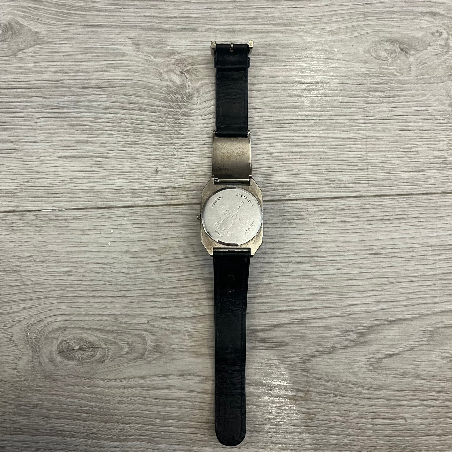 Hi-Tek Alexander “Jump Hour” 90's Analog Watch with a rare octagonal steel case and innovative rotation disc display. Hours appear in the left window and minutes in the right, revealed by the unique turnable cover. Made in England, this vintage 1990s watch features a chrome-plated stainless steel case, genuine leather strap, and an original design by Alexander Tasou of Hi-Tek Designs London. A true collector’s piece that is no longer in production.