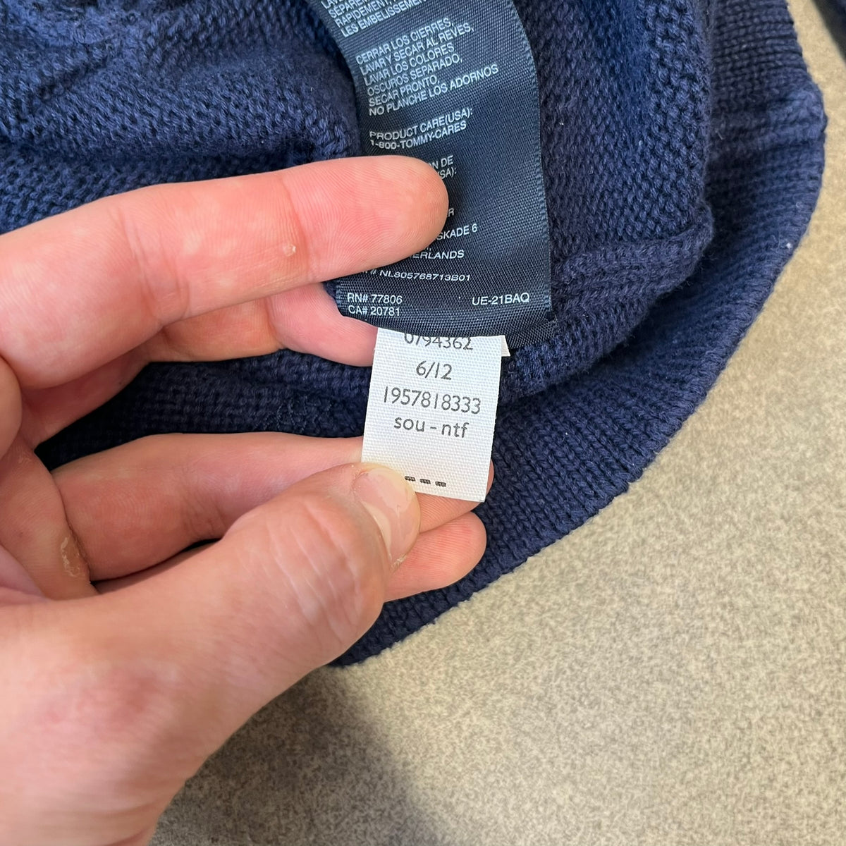 Hilfiger Denim 2012 Navy Varsity Cardigan is a navy cardigan with a white collar/hem trim and brown buttons, featuring two front pockets. It includes a large fuzzy "H" patch with text, two white straps on one sleeve, and a fuzzy white and navy "IV CHAMPS '85" patch.
