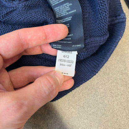 Hilfiger Denim 2012 Navy Varsity Cardigan is a navy cardigan with a white collar/hem trim and brown buttons, featuring two front pockets. It includes a large fuzzy "H" patch with text, two white straps on one sleeve, and a fuzzy white and navy "IV CHAMPS '85" patch.
