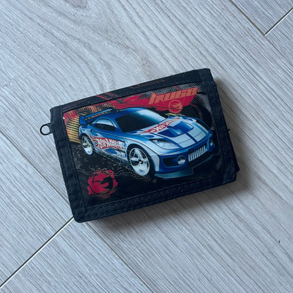 2008 Hot Wheels 24/Seven wallet in black with a detailed blue 24/Seven Car graphic under a protective plastic laminate. Includes Hot Wheels logo detailing, Mattel tags, and plenty of compartments for storage. A functional piece with nostalgic collector appeal.