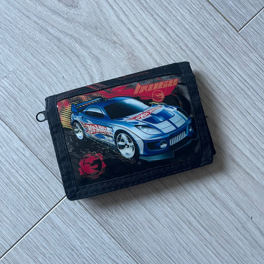 2008 Hot Wheels 24/Seven wallet in black with a detailed blue 24/Seven Car graphic under a protective plastic laminate. Includes Hot Wheels logo detailing, Mattel tags, and plenty of compartments for storage. A functional piece with nostalgic collector appeal.