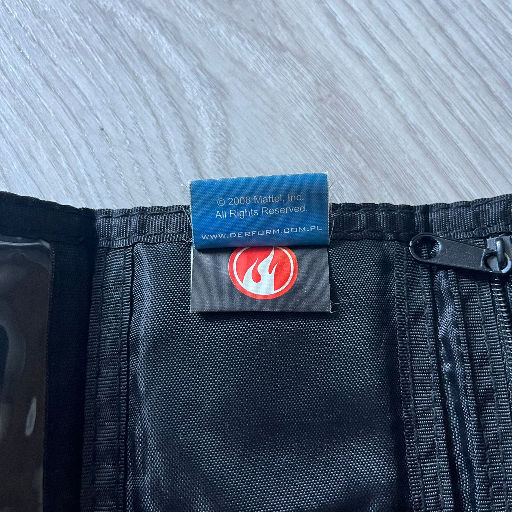 2008 Hot Wheels 24/Seven wallet in black with a detailed blue 24/Seven Car graphic under a protective plastic laminate. Includes Hot Wheels logo detailing, Mattel tags, and plenty of compartments for storage. A functional piece with nostalgic collector appeal.