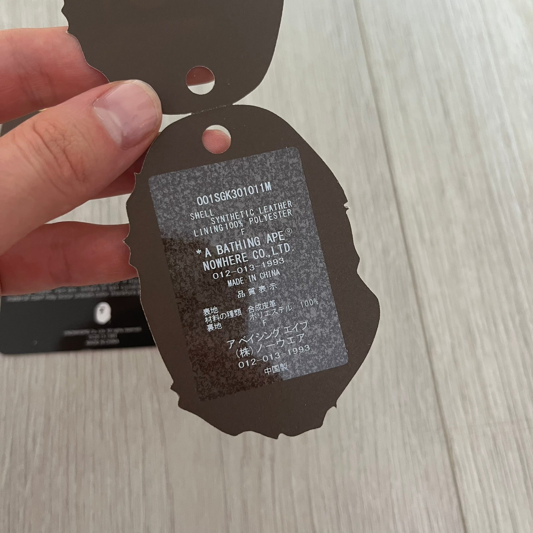 Close-up of a product tag held by a hand on a wooden surface
