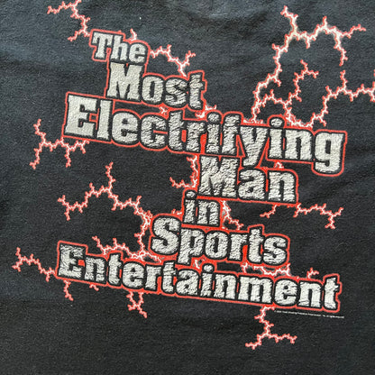 The Rock “Most Electrifying Man” 2000 Tee is a vintage WWE shirt featuring bold metallic-textured lettering with red lightning accents. The front proudly displays “The Rock,” while the back proclaims “The Most Electrifying Man in Sports Entertainment.” Licensed by World Wrestling Federation (WWF), this 2000 release is a must-have collectible for wrestling fans!