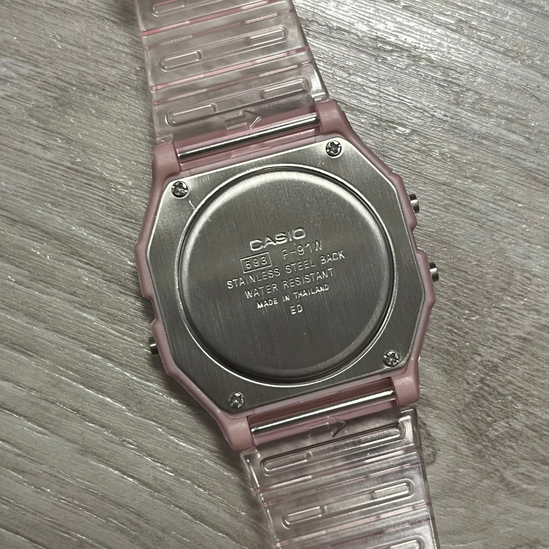 Back of a Casio watch with metal band on wooden surface