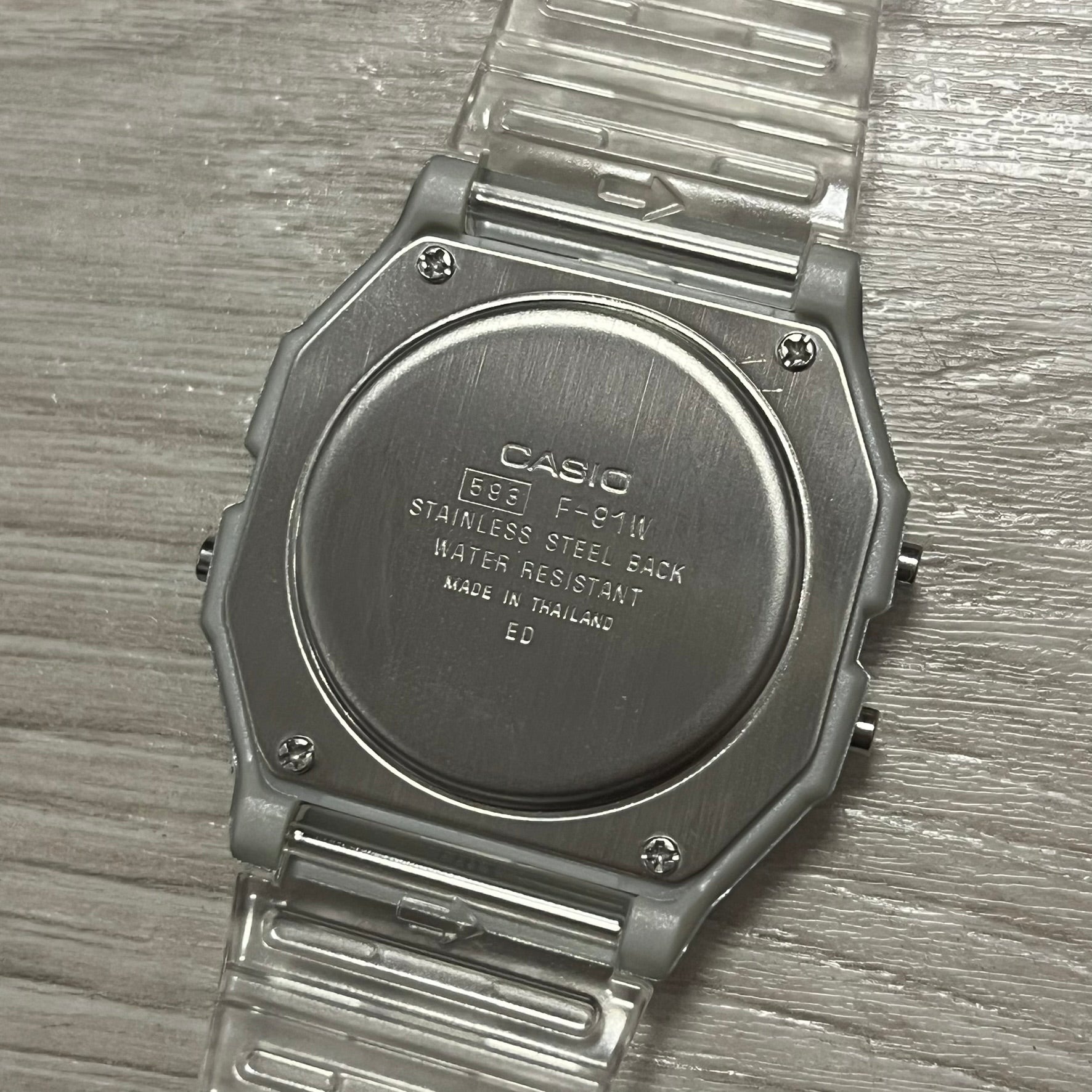 Back of a Casio watch with text on a wooden surface