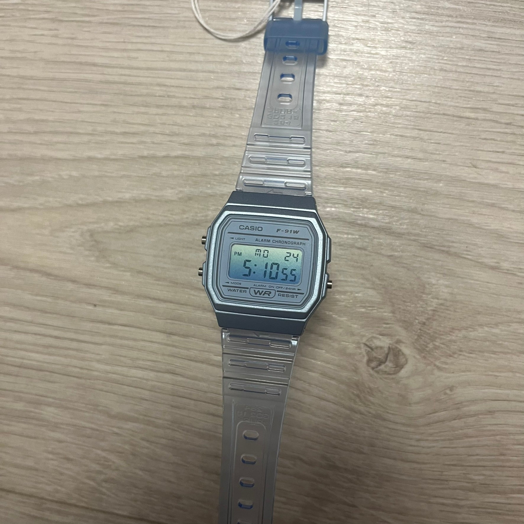 Digital watch with silver strap on wooden surface