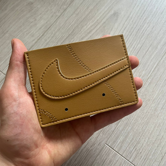 Brown leather wallet with a logo held in a hand on a wooden surface