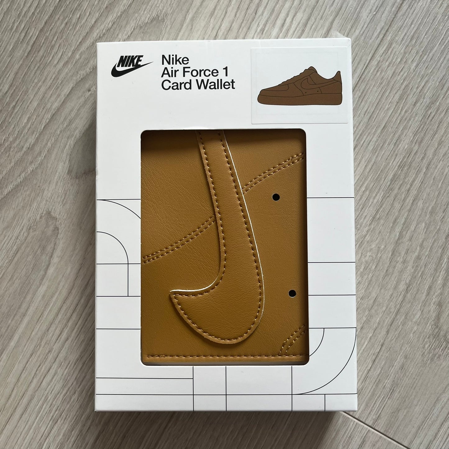 Brown card wallet in Nike Air Force 1 packaging on a wooden surface