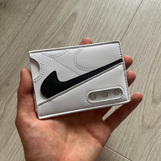 White cardholder with black Nike logo held in a hand on a wooden surface
