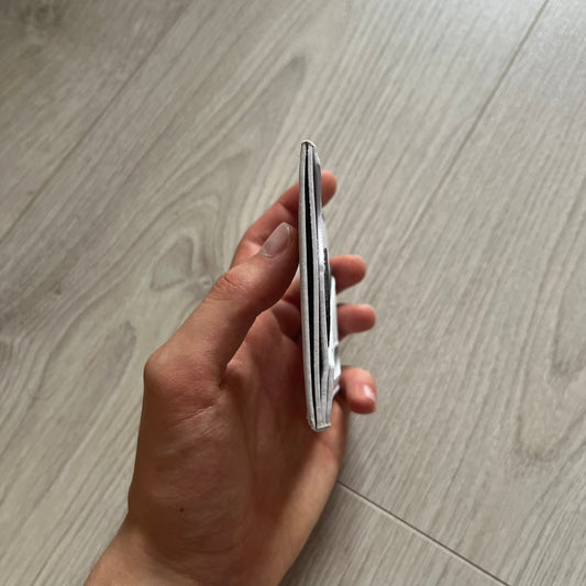 Hand holding a silver pocket knife on a wooden floor