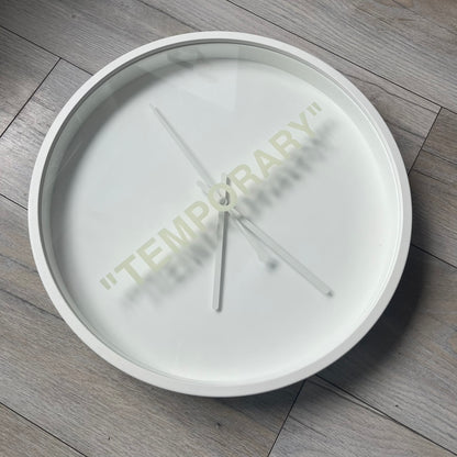 Ikea MARKERAD x Virgil Abloh “Temporary” Wall Clock is a white minimalist wall clock released on November 1, 2019 as part of the IKEA MARKERAD collaboration. It features a clean all-white design with a plexiglass cover and the word “TEMPORARY” printed across the face. The dial has no numerals, using only simple hour, minute, and second hands for time display.