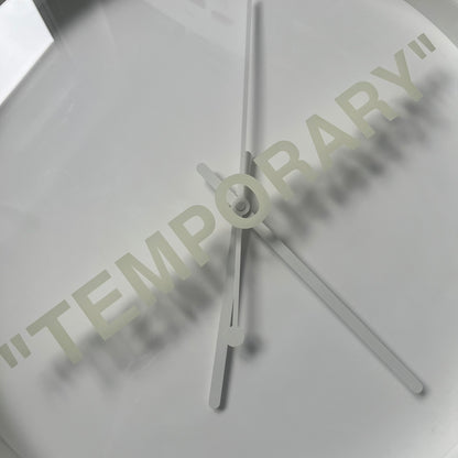 Ikea MARKERAD x Virgil Abloh “Temporary” Wall Clock is a white minimalist wall clock released on November 1, 2019 as part of the IKEA MARKERAD collaboration. It features a clean all-white design with a plexiglass cover and the word “TEMPORARY” printed across the face. The dial has no numerals, using only simple hour, minute, and second hands for time display.