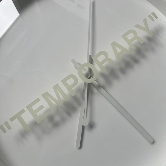 Ikea MARKERAD x Virgil Abloh “Temporary” Wall Clock is a white minimalist wall clock released on November 1, 2019 as part of the IKEA MARKERAD collaboration. It features a clean all-white design with a plexiglass cover and the word “TEMPORARY” printed across the face. The dial has no numerals, using only simple hour, minute, and second hands for time display.