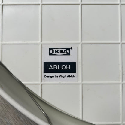Ikea MARKERAD x Virgil Abloh “Temporary” Wall Clock is a white minimalist wall clock released on November 1, 2019 as part of the IKEA MARKERAD collaboration. It features a clean all-white design with a plexiglass cover and the word “TEMPORARY” printed across the face. The dial has no numerals, using only simple hour, minute, and second hands for time display.