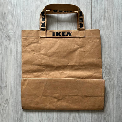 Ikea x Virgil Abloh Markerad "Sculpture" Carrier Bag from FW19 reimagines the iconic blue Frakta tote in reinforced brown paper. Embellished with Abloh’s signature quotation marks, the “SCULPTURE” print transforms a utilitarian object into conceptual design. A collectible symbol of functional art and everyday irony.