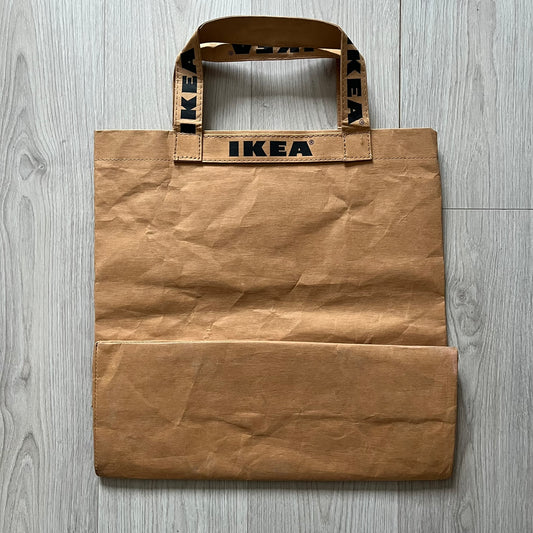 Ikea x Virgil Abloh Markerad "Sculpture" Carrier Bag from FW19 reimagines the iconic blue Frakta tote in reinforced brown paper. Embellished with Abloh’s signature quotation marks, the “SCULPTURE” print transforms a utilitarian object into conceptual design. A collectible symbol of functional art and everyday irony.