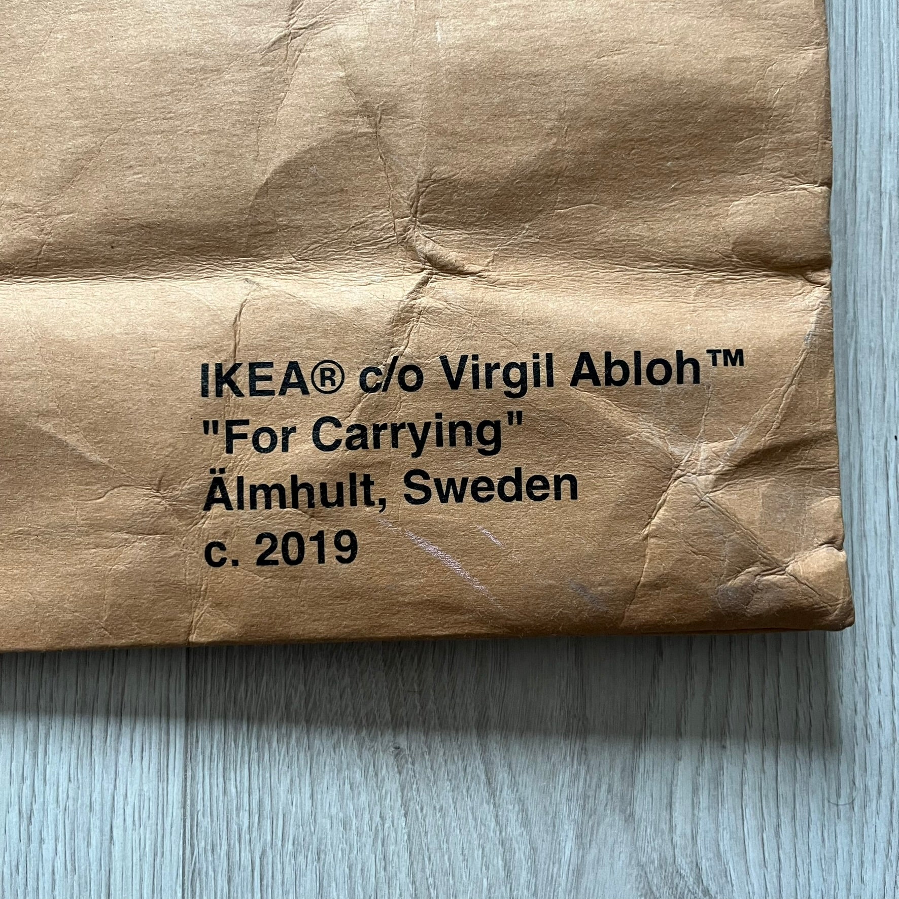 Ikea x Virgil Abloh Markerad "Sculpture" Carrier Bag from FW19 reimagines the iconic blue Frakta tote in reinforced brown paper. Embellished with Abloh’s signature quotation marks, the “SCULPTURE” print transforms a utilitarian object into conceptual design. A collectible symbol of functional art and everyday irony.