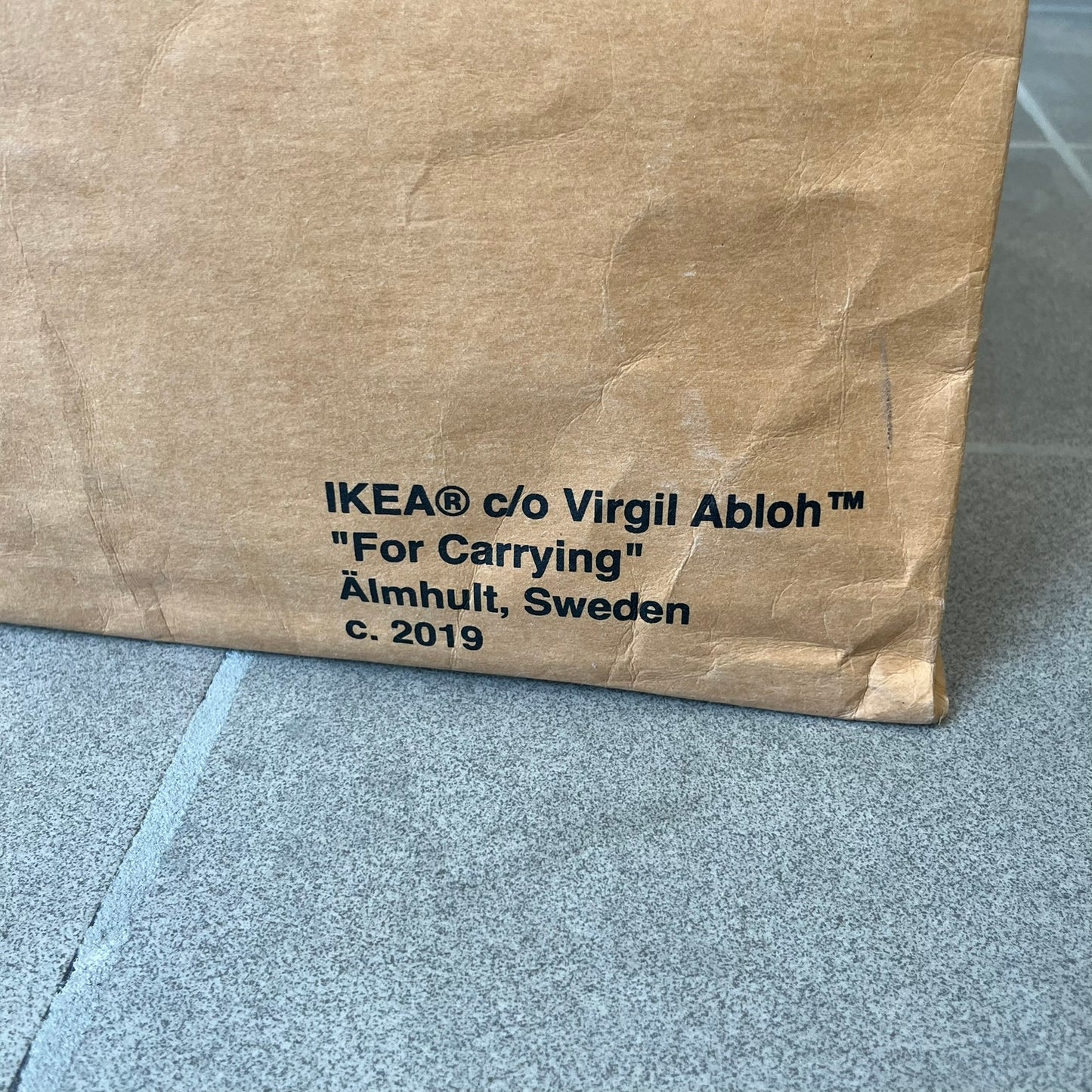 Ikea x Virgil Abloh Markerad "Sculpture" Carrier Bag from FW19 reimagines the iconic blue Frakta tote in reinforced brown paper. Embellished with Abloh’s signature quotation marks, the “SCULPTURE” print transforms a utilitarian object into conceptual design. A collectible symbol of functional art and everyday irony.