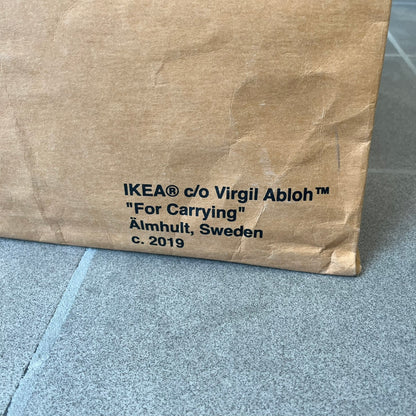 Ikea x Virgil Abloh Markerad "Sculpture" Carrier Bag from FW19 reimagines the iconic blue Frakta tote in reinforced brown paper. Embellished with Abloh’s signature quotation marks, the “SCULPTURE” print transforms a utilitarian object into conceptual design. A collectible symbol of functional art and everyday irony.