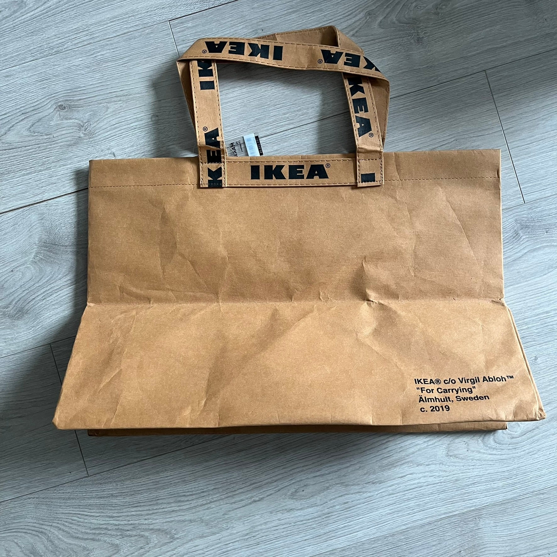 Ikea x Virgil Abloh Markerad "Sculpture" Carrier Bag from FW19 reimagines the iconic blue Frakta tote in reinforced brown paper. Embellished with Abloh’s signature quotation marks, the “SCULPTURE” print transforms a utilitarian object into conceptual design. A collectible symbol of functional art and everyday irony.