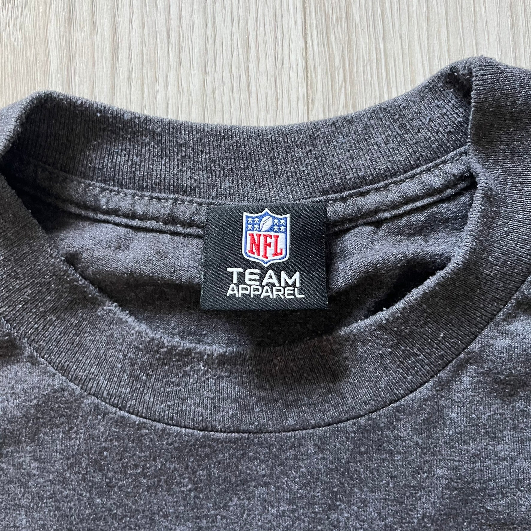 Gray shirt with NFL Team Apparel label on a wooden surface