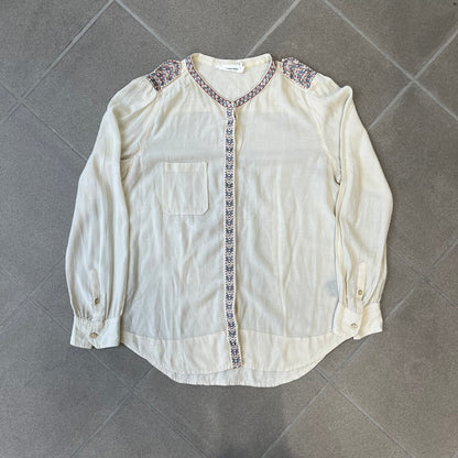 Isabel Marant Étoile Cream Embroidered Blouse features a lightweight, semi-sheer cream fabric with multicolored embroidery along the front button placket, collar, and shoulder details. It has a button-up front and one chest pocket.