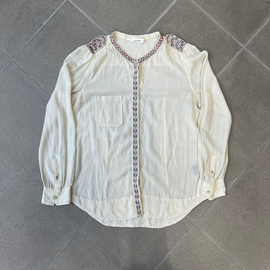 Isabel Marant Étoile Cream Embroidered Blouse features a lightweight, semi-sheer cream fabric with multicolored embroidery along the front button placket, collar, and shoulder details. It has a button-up front and one chest pocket.