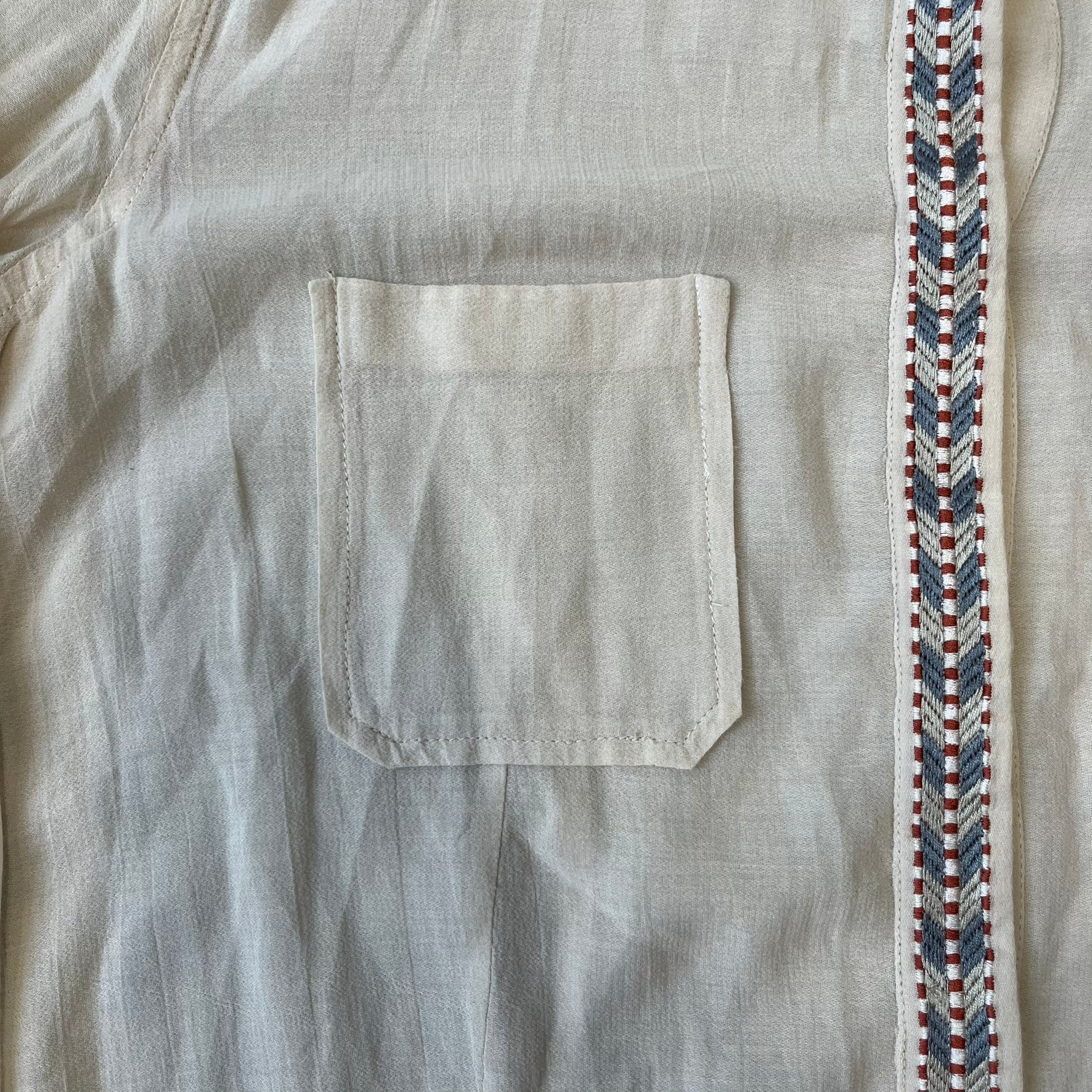 Isabel Marant Étoile Cream Embroidered Blouse features a lightweight, semi-sheer cream fabric with multicolored embroidery along the front button placket, collar, and shoulder details. It has a button-up front and one chest pocket.