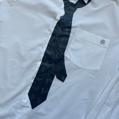 JC De Castelbajac AW08 Loose Tie Shirt is a white long-sleeve shirt from the Autumn/Winter 2008 collection, made in Italy from 100% cotton. The design features a printed navy tie with JC monogram on the front, a chest pocket with small logo embroidery, and additional logo embroidery on the back below the collar and on the sleeve. It includes mother-of-pearl buttons with contrasting white and navy detailing, matching the printed tie graphic.