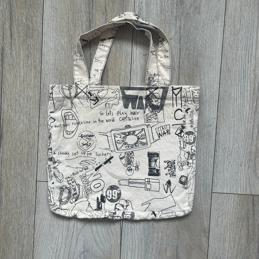 Jeremy Scott 2004 Chicks on Speed: It’s a Project Tote Bag is a cream canvas tote featuring multiple black hand-drawn style graphics including symbols, objects, and abstract motifs such as text elements, crossed-out luxury references, lips, watches, chains, and figures. The bag was originally part of a limited art publication kit released in 2004. It came with additional included items such as a book, poster, CD, clothing pattern, and fabric components as part of the full “Chicks on Speed: It’s a Project” s