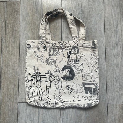Jeremy Scott 2004 Chicks on Speed: It’s a Project Tote Bag is a cream canvas tote featuring multiple black hand-drawn style graphics including symbols, objects, and abstract motifs such as text elements, crossed-out luxury references, lips, watches, chains, and figures. The bag was originally part of a limited art publication kit released in 2004. It came with additional included items such as a book, poster, CD, clothing pattern, and fabric components as part of the full “Chicks on Speed: It’s a Project” s