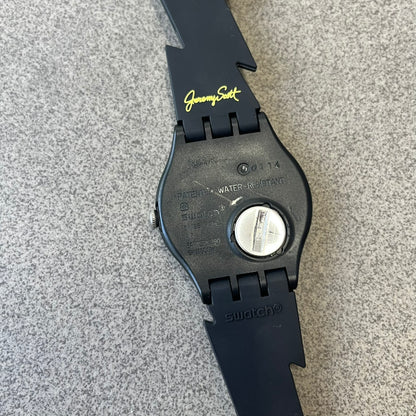 Jeremy Scott Swatch 2011 Lightning Flash Analog Watch (SUOZ104) is a limited-edition watch released in March 2011 from Jeremy Scott's first collaboration with Swatch. It features a black and yellow design with lightning bolt-shaped rubber straps, a yellow dial with a black case, lightning bolt-shaped hands, and a Jeremy Scott signature on the back.
