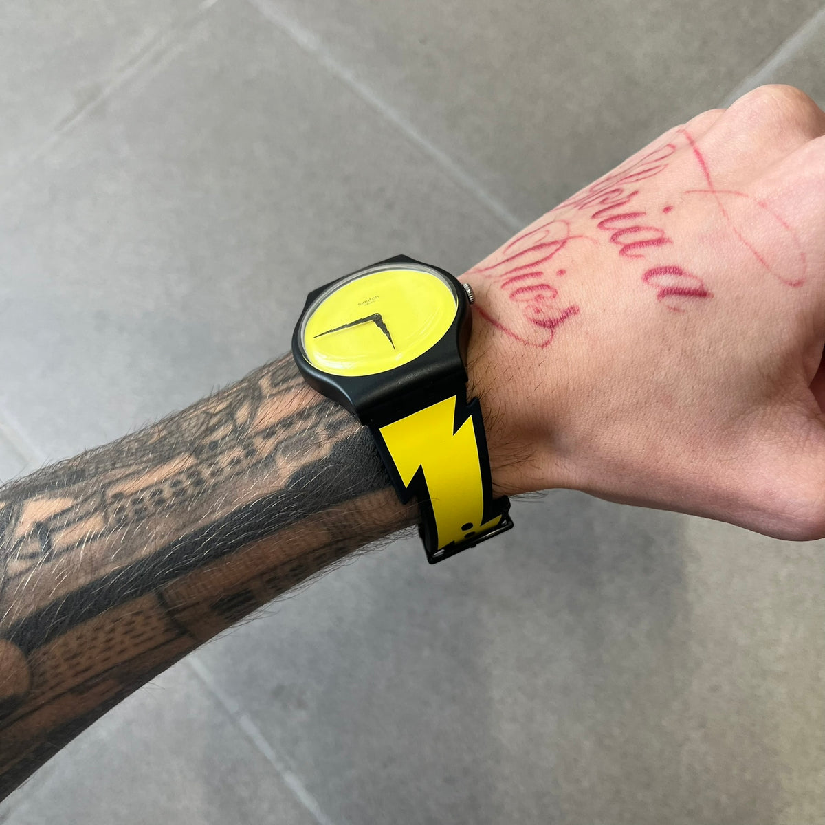 Jeremy Scott Swatch 2011 Lightning Flash Analog Watch (SUOZ104) is a limited-edition watch released in March 2011 from Jeremy Scott's first collaboration with Swatch. It features a black and yellow design with lightning bolt-shaped rubber straps, a yellow dial with a black case, lightning bolt-shaped hands, and a Jeremy Scott signature on the back.