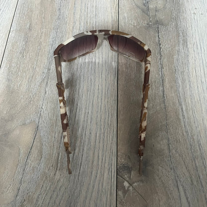 Jeremy Scott x Linda Farrow SS2013 Desert Camo M16 Rifle Sunglasses (JSARMYC4SUN) are a statement eyewear piece from the Spring/Summer 2013 collaboration. The design features full camo brown and beige frames with red/pink lenses, while the arms are constructed as detailed 3D M16 rifle shapes extending toward the front of the frame. The model includes Jeremy Scott branding on the inner arms and is produced in a high-detail acetate construction.