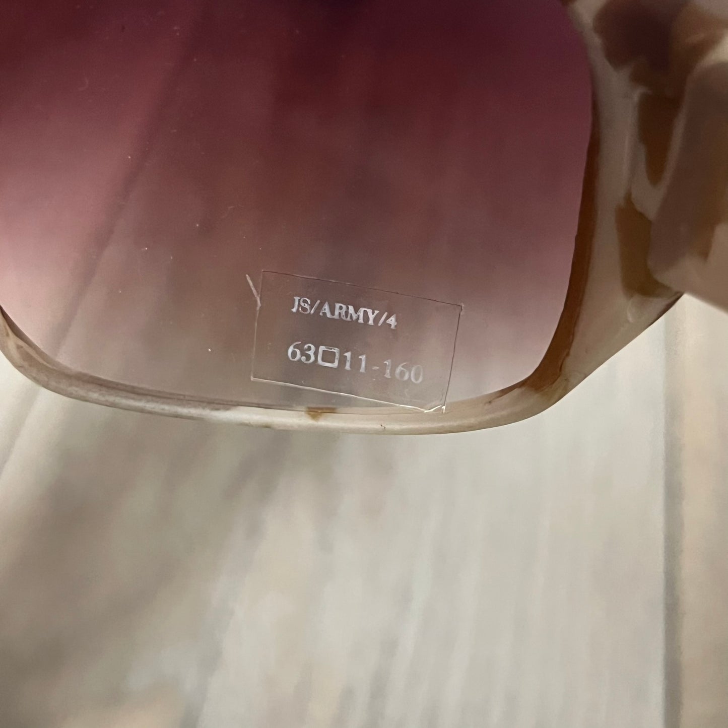 Jeremy Scott x Linda Farrow SS2013 Desert Camo M16 Rifle Sunglasses (JSARMYC4SUN) are a statement eyewear piece from the Spring/Summer 2013 collaboration. The design features full camo brown and beige frames with red/pink lenses, while the arms are constructed as detailed 3D M16 rifle shapes extending toward the front of the frame. The model includes Jeremy Scott branding on the inner arms and is produced in a high-detail acetate construction.