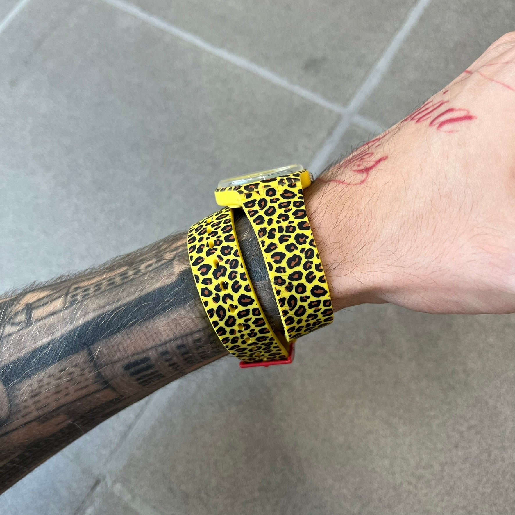 Swatch x Jeremy Scott 2011 Punk Analog Watch GZ251 is a quartz watch from the Gent Original line featuring a bright green dial with black hands and a plastic case. The design includes a comically long silicone strap with leopard print that wraps twice around the wrist, secured with multiple yellow loops, and Jeremy Scott branding on the upper strap.