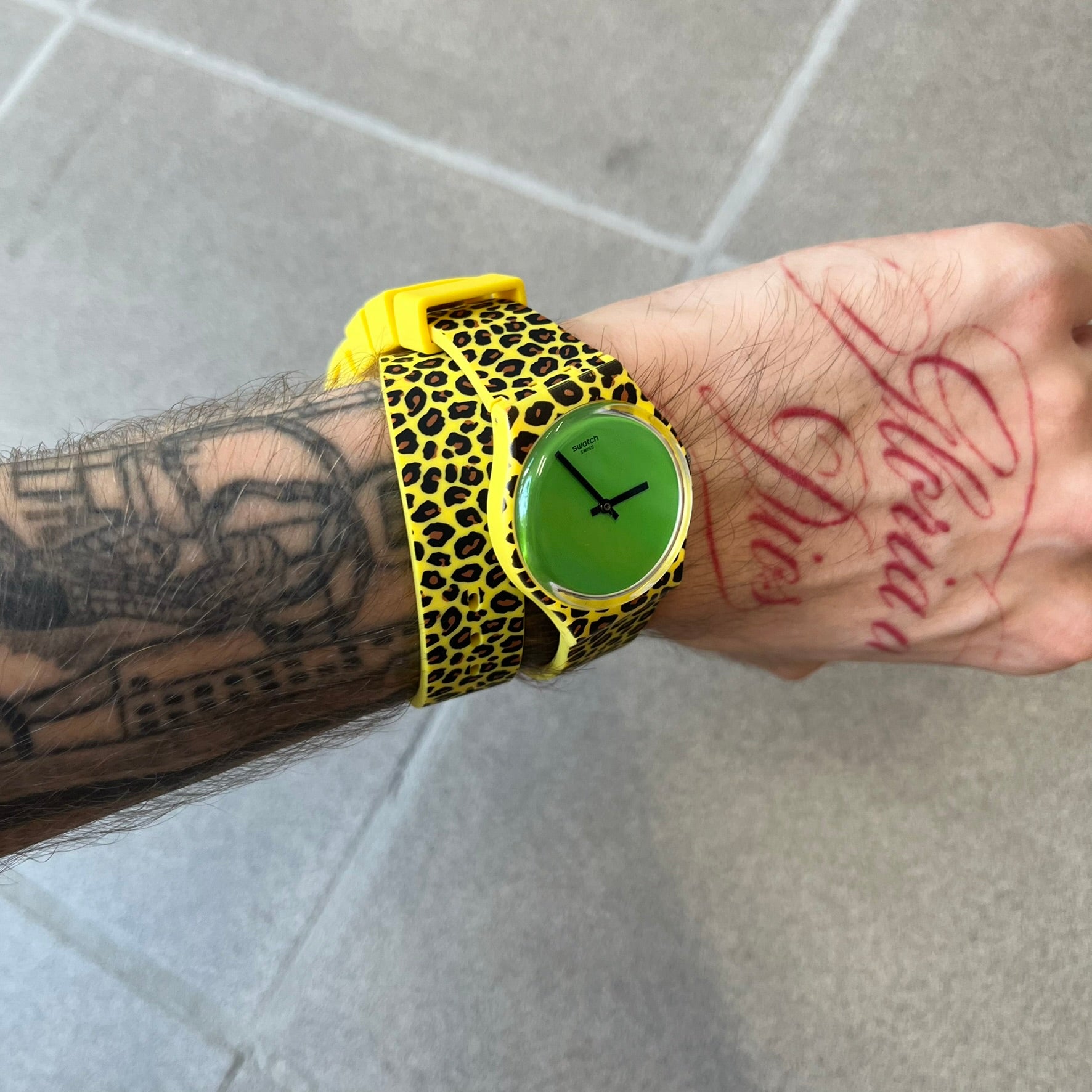 Swatch x Jeremy Scott 2011 Punk Analog Watch GZ251 is a quartz watch from the Gent Original line featuring a bright green dial with black hands and a plastic case. The design includes a comically long silicone strap with leopard print that wraps twice around the wrist, secured with multiple yellow loops, and Jeremy Scott branding on the upper strap.