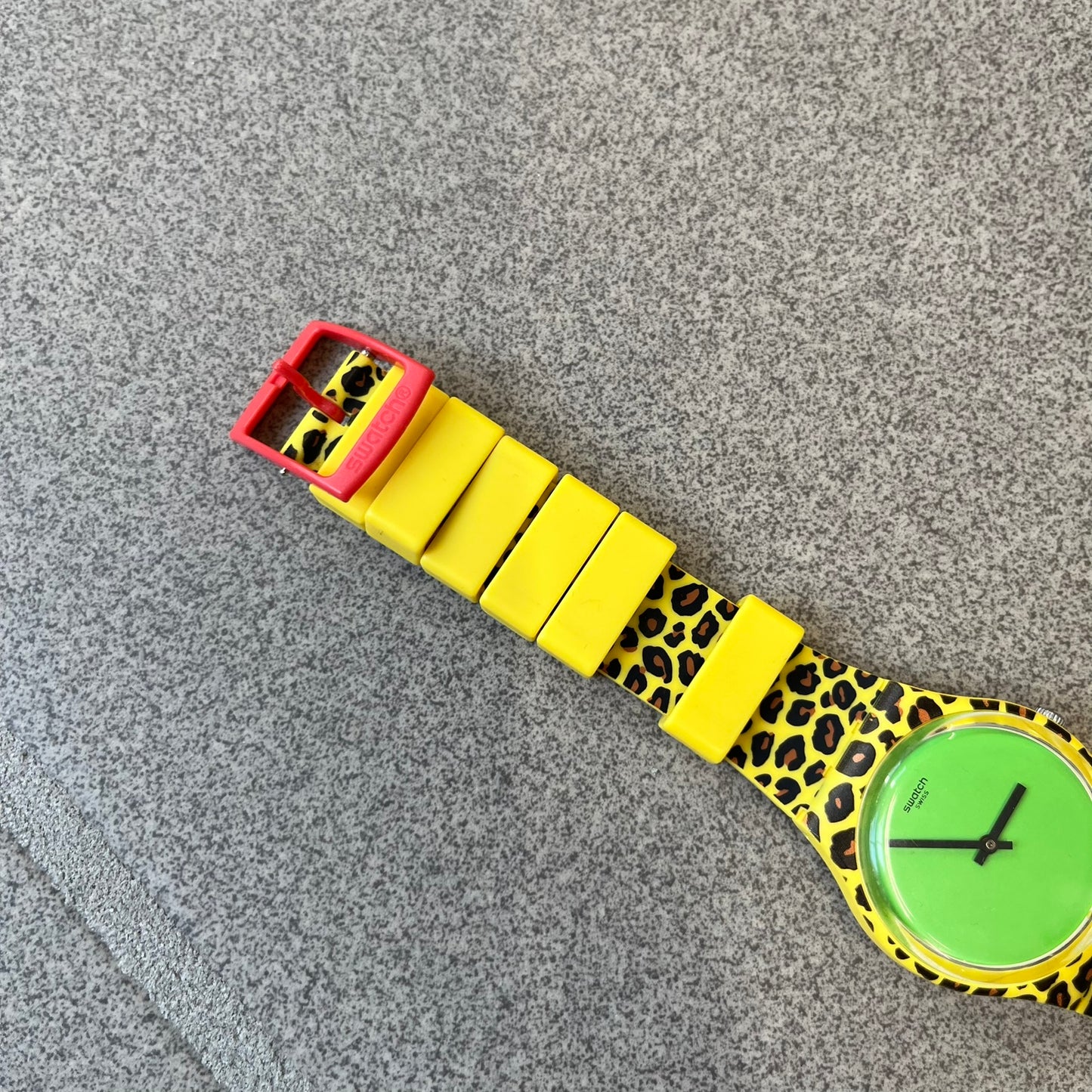 Swatch x Jeremy Scott 2011 Punk Analog Watch GZ251 is a quartz watch from the Gent Original line featuring a bright green dial with black hands and a plastic case. The design includes a comically long silicone strap with leopard print that wraps twice around the wrist, secured with multiple yellow loops, and Jeremy Scott branding on the upper strap.