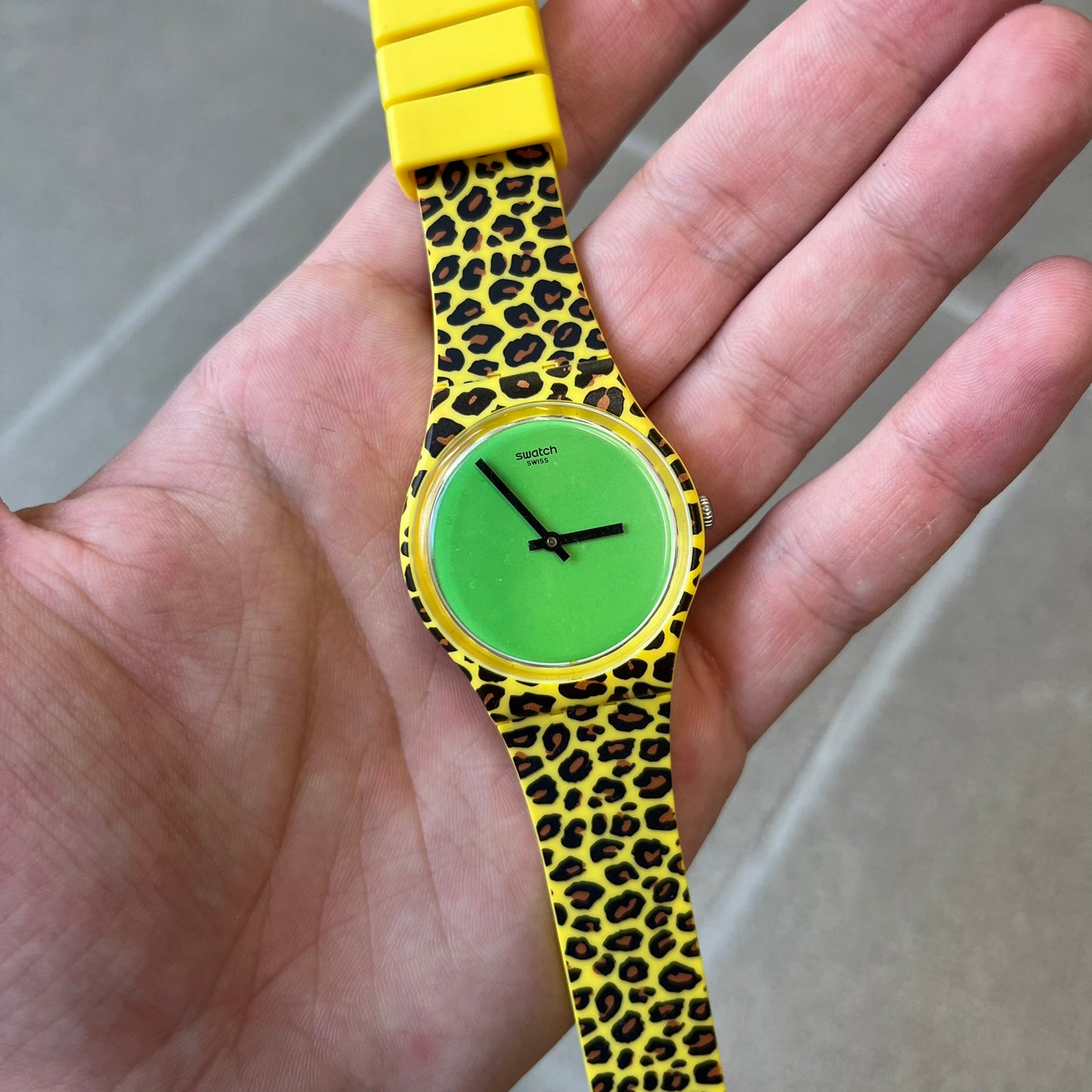 Swatch x Jeremy Scott 2011 Punk Analog Watch GZ251 is a quartz watch from the Gent Original line featuring a bright green dial with black hands and a plastic case. The design includes a comically long silicone strap with leopard print that wraps twice around the wrist, secured with multiple yellow loops, and Jeremy Scott branding on the upper strap.