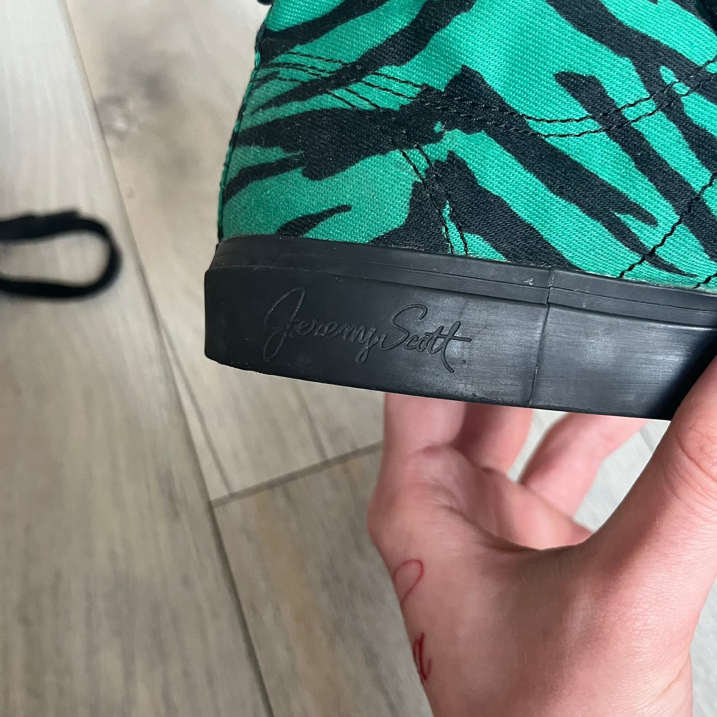 Jeremy Scott x adidas 2014 Nizza Hi “Forest Green” Sneakers are made with a forest green canvas upper featuring an all-over black tiger print. The high-top shoes include rubber soles and standard adidas Nizza tooling. This model was released in 2014 in a green and black colorway as part of the Jeremy Scott x adidas collaboration.