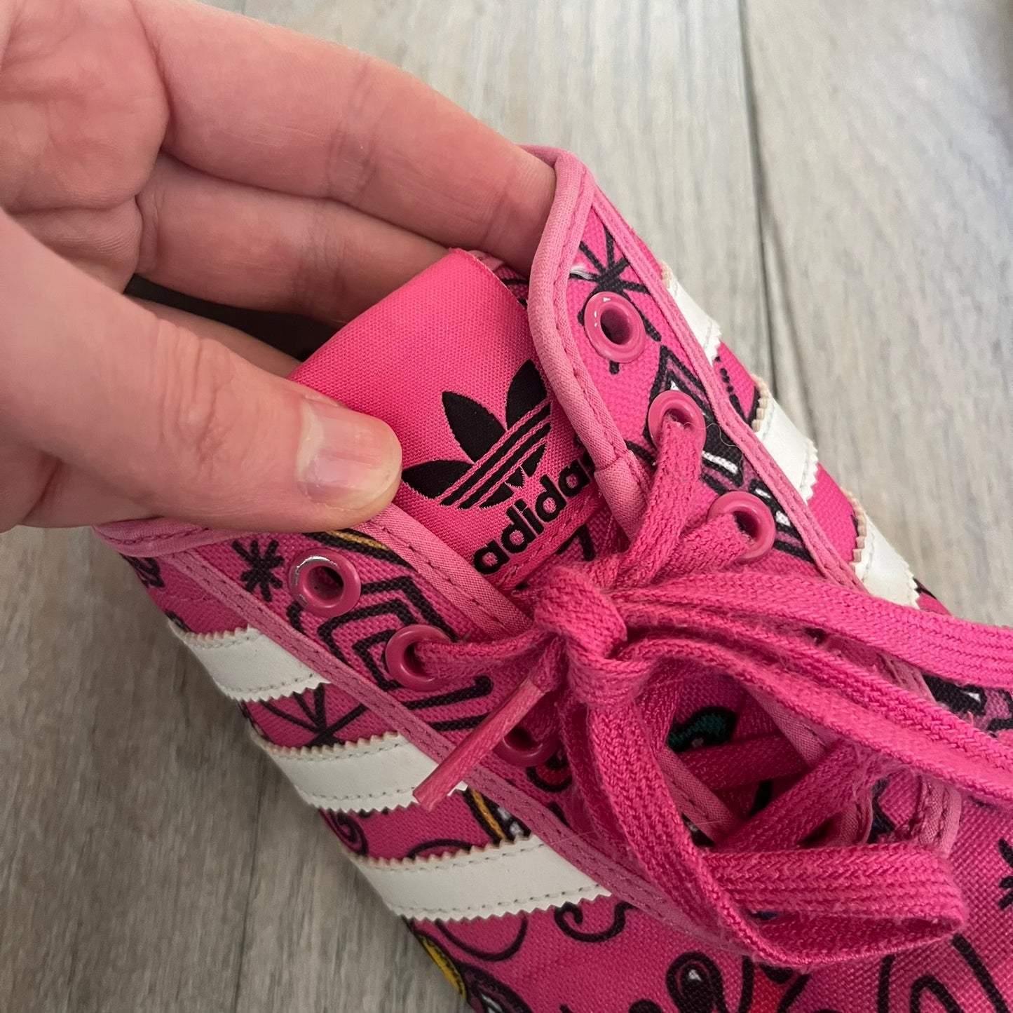 Jeremy Scott x adidas 2014 P-Sole “Pink” Sneakers feature a pink canvas upper with white leather adidas stripes and multicolored graphic prints. Released in 2014, they are part of the P-Sole line in the collaboration between adidas Originals, Jeremy Scott, and Kenny Scharf. The shoes include standard rubber soles and lace-up closure.