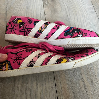 Jeremy Scott x adidas 2014 P-Sole “Pink” Sneakers feature a pink canvas upper with white leather adidas stripes and multicolored graphic prints. Released in 2014, they are part of the P-Sole line in the collaboration between adidas Originals, Jeremy Scott, and Kenny Scharf. The shoes include standard rubber soles and lace-up closure.