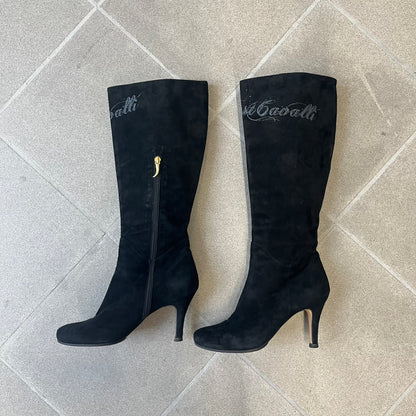 Just Cavalli 2000's Black Suede Boots are made in Italy, featuring black suede uppers with a beige sole and "Just Cavalli" branding on the bottom. A glittery silver "Just Cavalli" text logo appears at the top of the boot, with a side zipper running from the midpoint down, finished with a gold Just Cavalli horn zipper pull.
