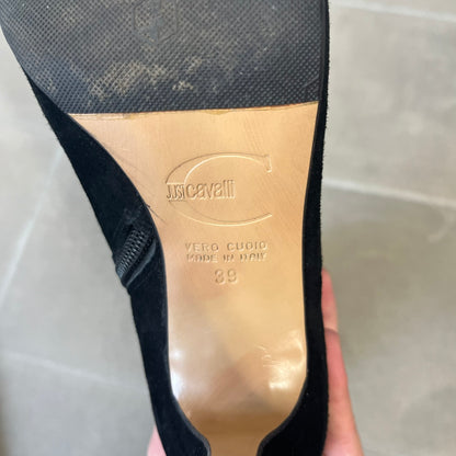 Just Cavalli 2000's Black Suede Boots are made in Italy, featuring black suede uppers with a beige sole and "Just Cavalli" branding on the bottom. A glittery silver "Just Cavalli" text logo appears at the top of the boot, with a side zipper running from the midpoint down, finished with a gold Just Cavalli horn zipper pull.